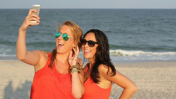 girls in sunglasses with cell phone - taking Instagram photo